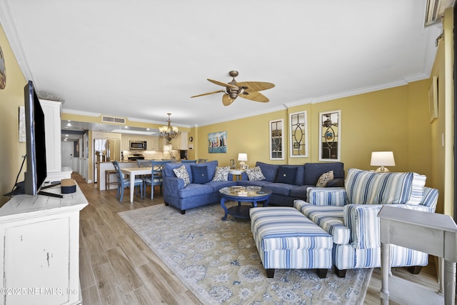 living room with ceiling fan with notable chandelier, ornamental molding, and light wood-type flooring