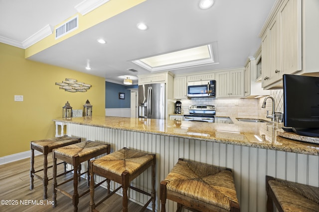 kitchen with sink, crown molding, kitchen peninsula, stainless steel appliances, and decorative backsplash