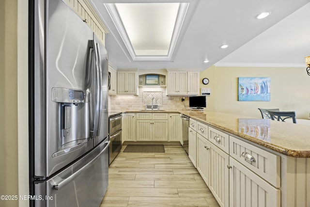 kitchen with tasteful backsplash, stainless steel appliances, kitchen peninsula, and cream cabinets