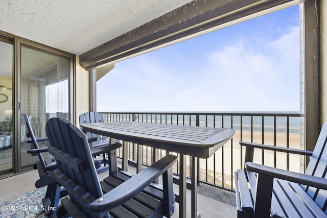 balcony featuring a beach view and a water view