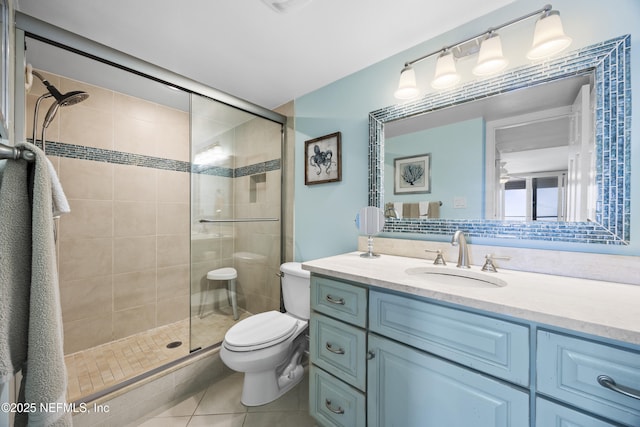 bathroom featuring tile patterned floors, toilet, a shower with door, and vanity