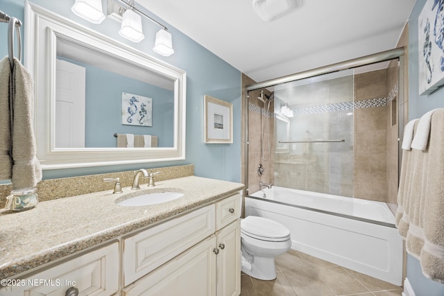 full bathroom with tile patterned flooring, vanity, bath / shower combo with glass door, and toilet