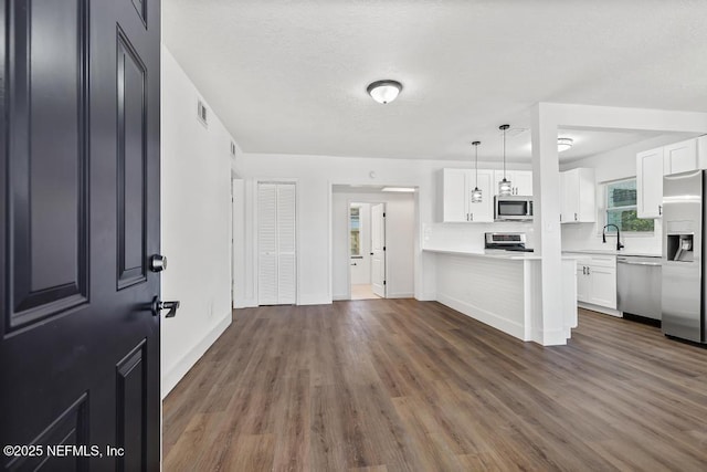 kitchen featuring white cabinetry, decorative light fixtures, dark hardwood / wood-style flooring, and appliances with stainless steel finishes