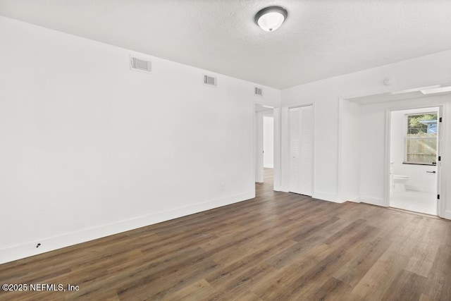 unfurnished room featuring dark hardwood / wood-style flooring and a textured ceiling