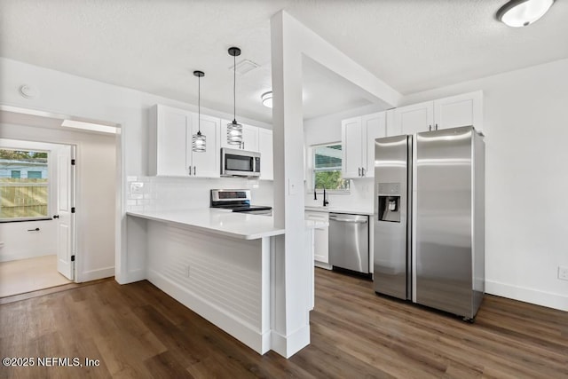 kitchen featuring sink, white cabinets, hanging light fixtures, kitchen peninsula, and stainless steel appliances