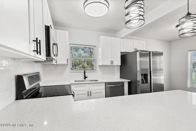 kitchen with white cabinetry, stainless steel appliances, sink, and pendant lighting