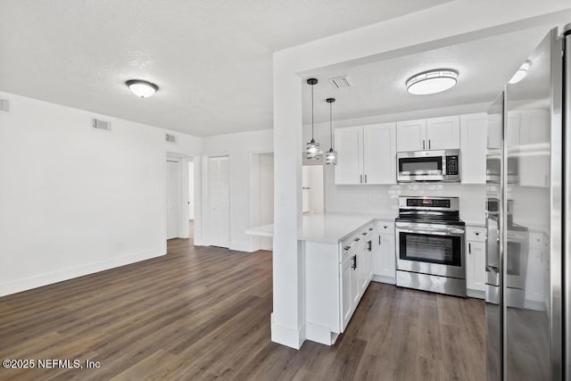 kitchen featuring decorative light fixtures, dark wood-type flooring, white cabinets, and appliances with stainless steel finishes