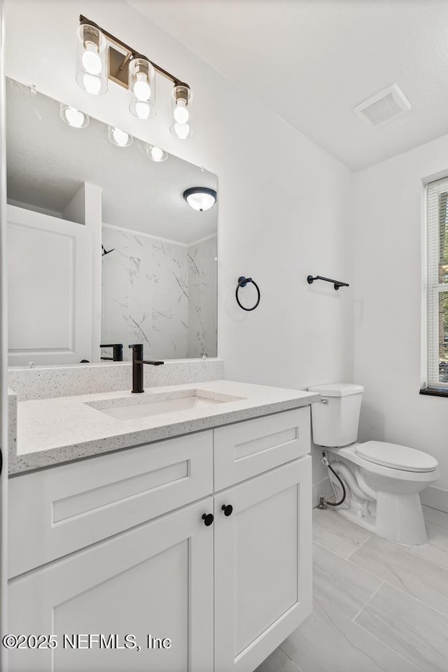 bathroom with vanity, toilet, and a shower