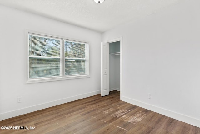 unfurnished bedroom with hardwood / wood-style flooring, a closet, and a textured ceiling