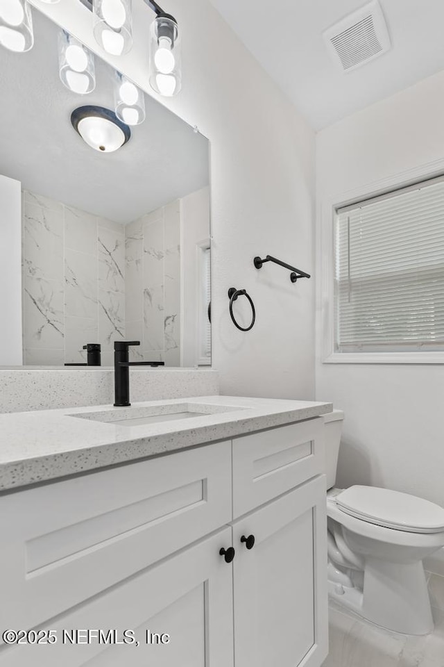 bathroom featuring vanity, toilet, and a shower