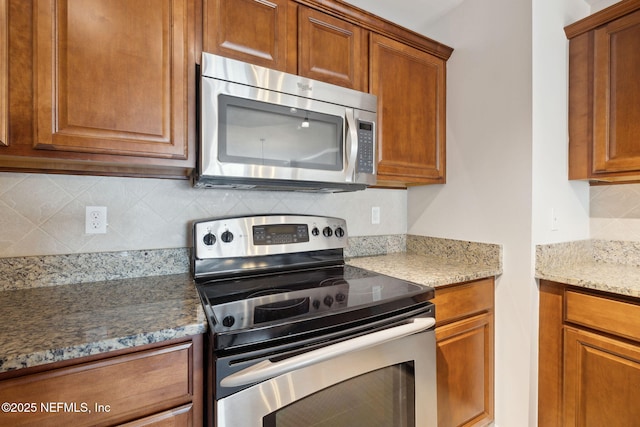 kitchen featuring light stone counters, decorative backsplash, and stainless steel appliances