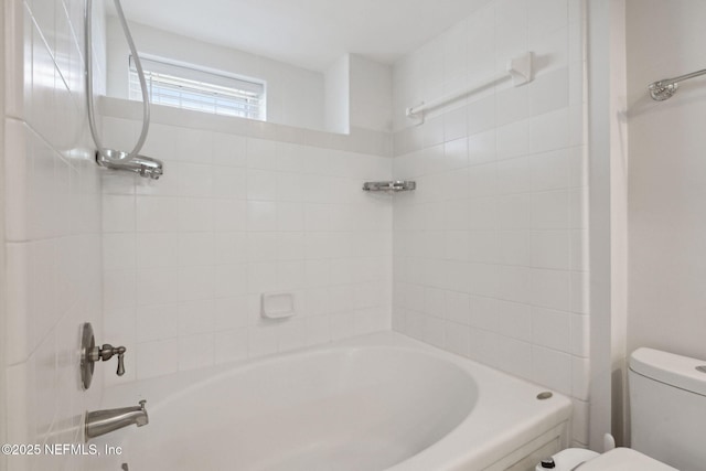 bathroom featuring tiled shower / bath and toilet