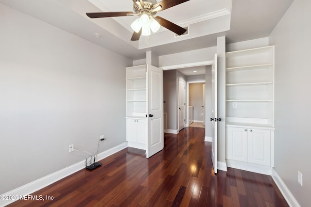 spare room featuring dark wood-type flooring, ceiling fan, and a tray ceiling