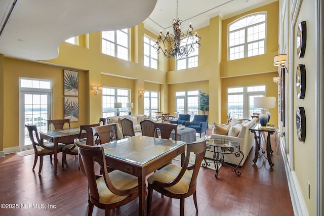 dining room with dark wood-type flooring, a healthy amount of sunlight, and a chandelier