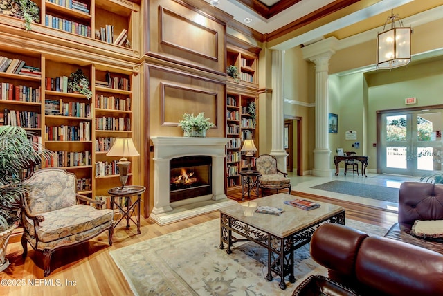 living area with ornate columns, ornamental molding, light hardwood / wood-style floors, and french doors