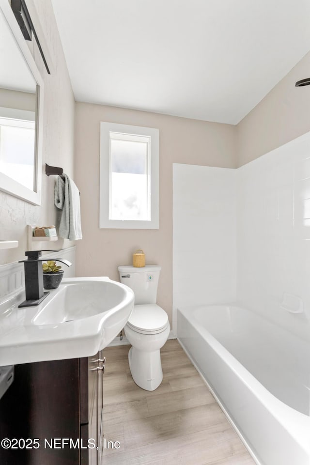 bathroom featuring hardwood / wood-style flooring, shower / tub combination, and toilet