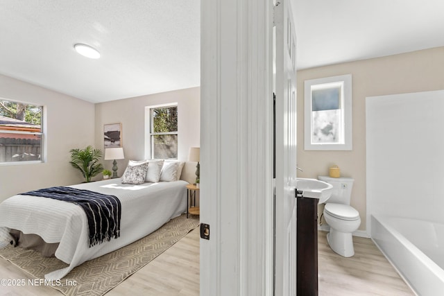 bedroom featuring multiple windows and light hardwood / wood-style floors