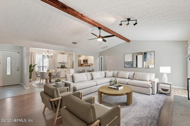 living room featuring ceiling fan with notable chandelier, light hardwood / wood-style floors, lofted ceiling with beams, and a textured ceiling