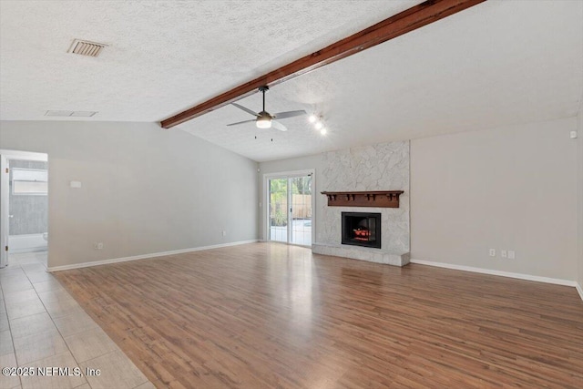 unfurnished living room featuring vaulted ceiling with beams, light hardwood / wood-style flooring, a textured ceiling, ceiling fan, and a premium fireplace