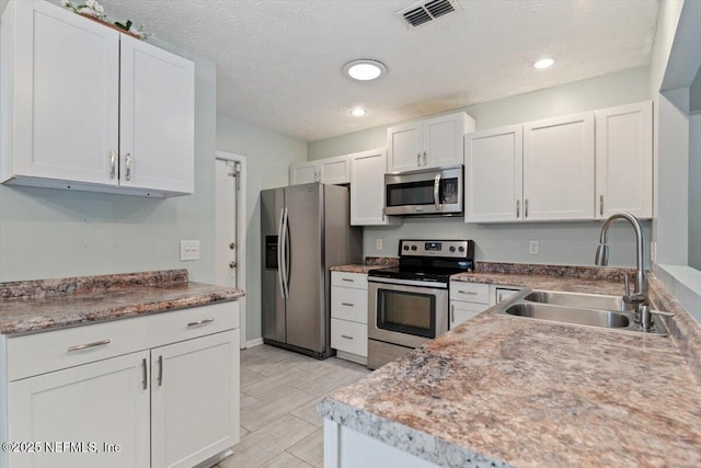 kitchen featuring white cabinetry, sink, stainless steel appliances, and a textured ceiling