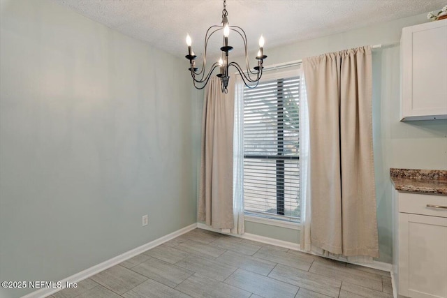 unfurnished dining area featuring a notable chandelier and a textured ceiling