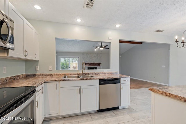 kitchen featuring appliances with stainless steel finishes, sink, ceiling fan with notable chandelier, and white cabinets