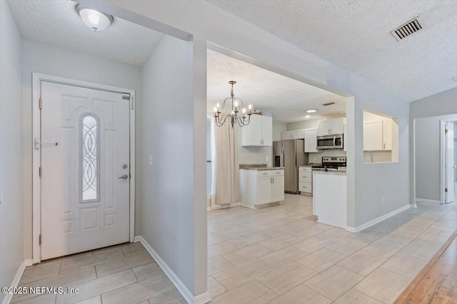 entryway featuring light wood-type flooring, a textured ceiling, and a chandelier