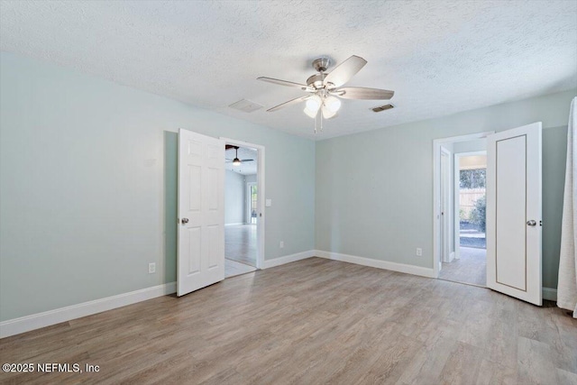 spare room featuring a wealth of natural light, a textured ceiling, and light hardwood / wood-style flooring