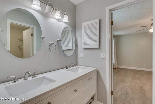 bathroom featuring hardwood / wood-style flooring, ceiling fan, vanity, and a textured ceiling