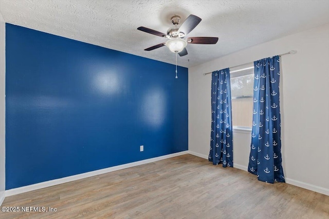 spare room featuring ceiling fan, light hardwood / wood-style flooring, and a textured ceiling