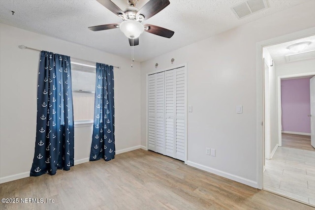 unfurnished bedroom featuring a textured ceiling, light wood-type flooring, and a closet