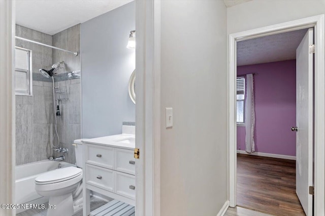 full bathroom featuring tiled shower / bath, hardwood / wood-style floors, vanity, toilet, and a textured ceiling