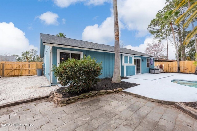 rear view of property featuring a fenced in pool and a patio