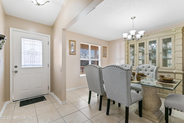 tiled dining area featuring a notable chandelier and a textured ceiling