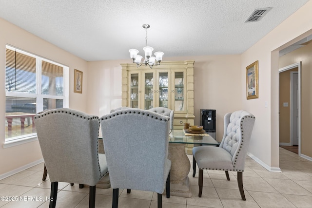 tiled dining room with a notable chandelier and a textured ceiling