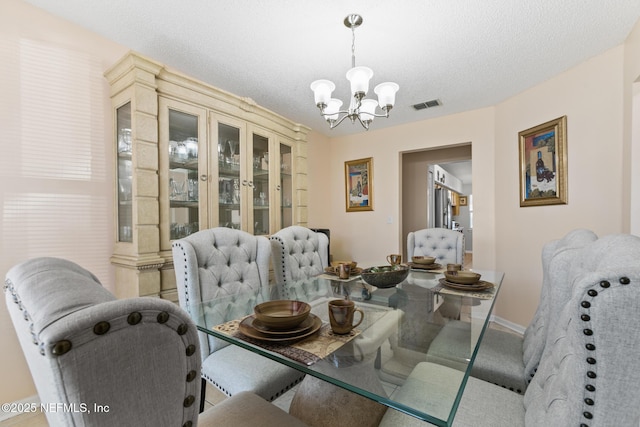 dining room with a chandelier and a textured ceiling