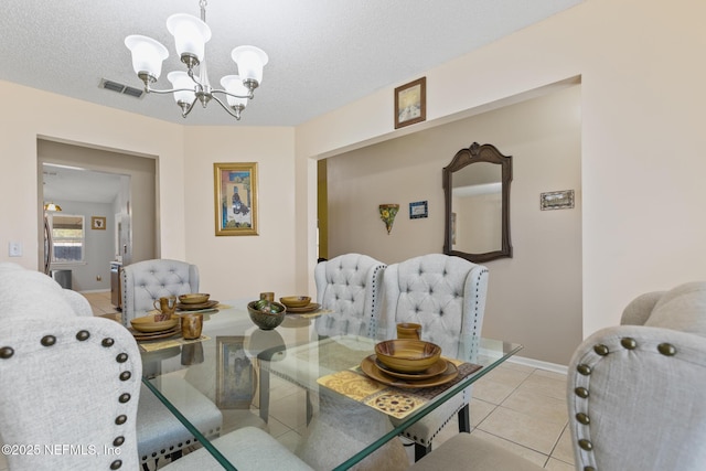 tiled dining space featuring an inviting chandelier and a textured ceiling