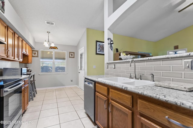 kitchen with sink, light tile patterned floors, appliances with stainless steel finishes, decorative light fixtures, and a chandelier