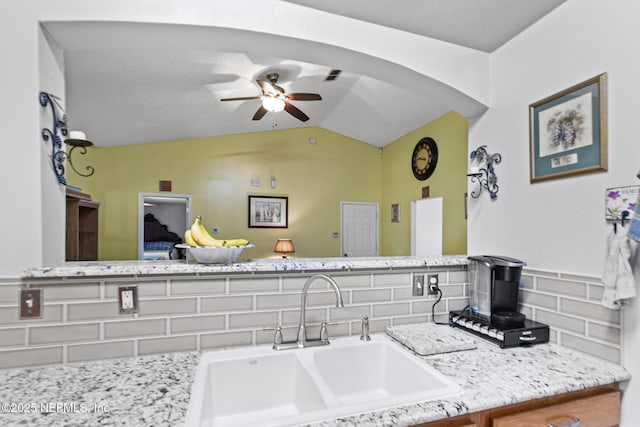 interior space featuring tasteful backsplash, lofted ceiling, sink, and ceiling fan