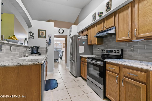 kitchen featuring light tile patterned floors, sink, appliances with stainless steel finishes, light stone countertops, and vaulted ceiling