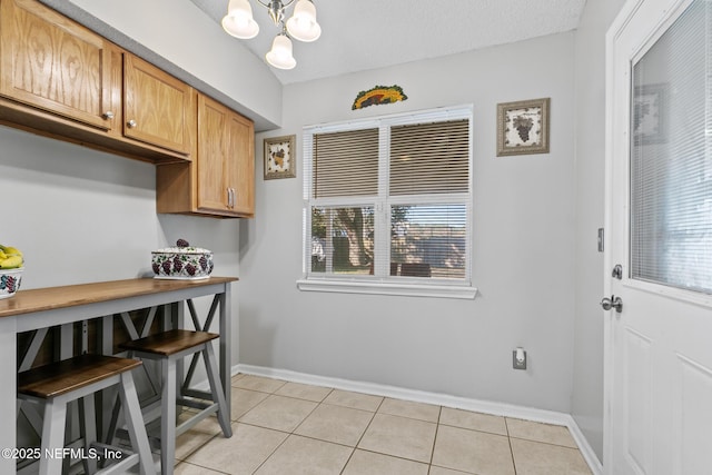 kitchen with light tile patterned floors, a textured ceiling, and an inviting chandelier