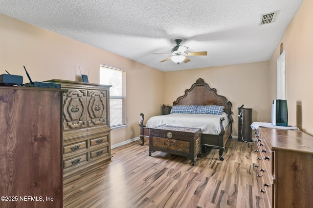 bedroom featuring ceiling fan, a textured ceiling, and light wood-type flooring