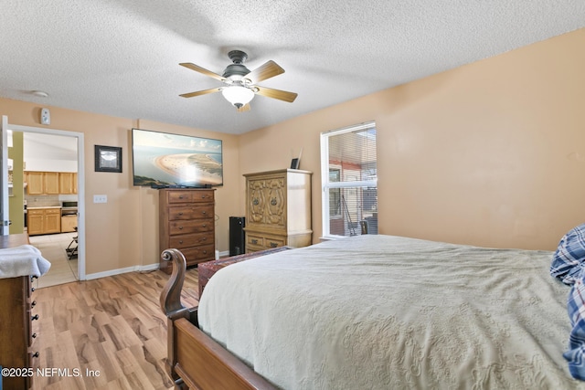 bedroom with ceiling fan, light hardwood / wood-style flooring, and a textured ceiling