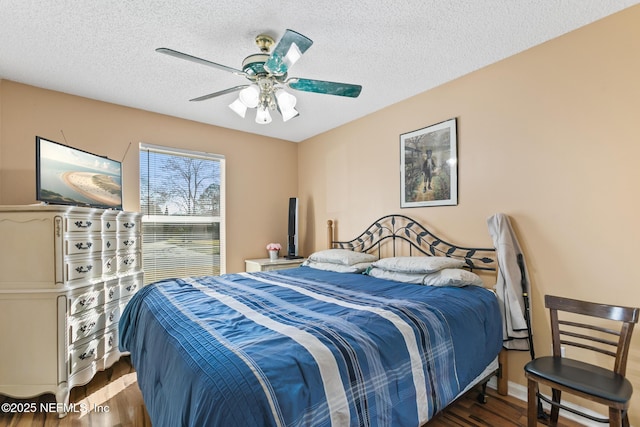 bedroom featuring ceiling fan, dark hardwood / wood-style floors, and a textured ceiling