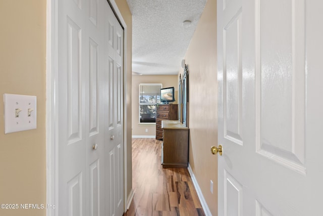 hallway with hardwood / wood-style floors and a textured ceiling