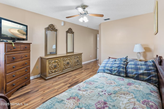 bedroom featuring ceiling fan, a textured ceiling, and light wood-type flooring