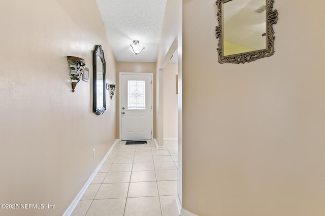 doorway with a textured ceiling and light tile patterned floors