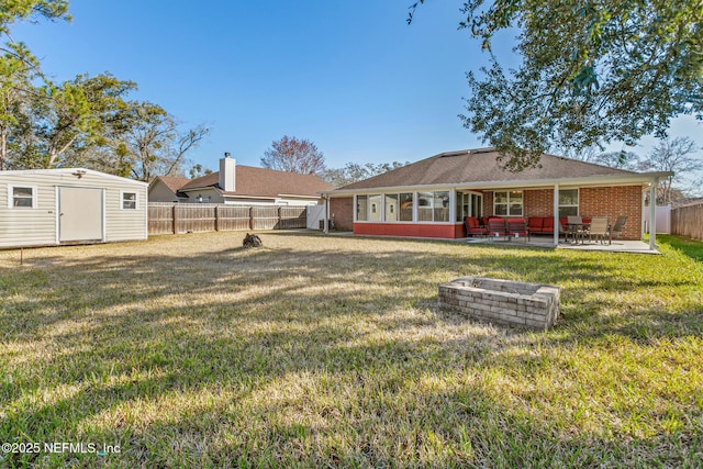 back of property featuring a yard, a shed, a patio area, and a fire pit