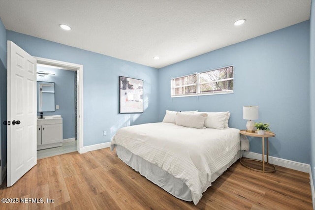 bedroom with connected bathroom and light hardwood / wood-style flooring