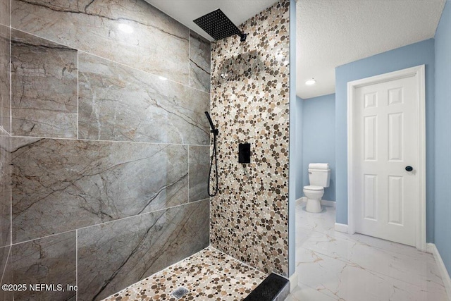 bathroom featuring a textured ceiling, toilet, and tiled shower